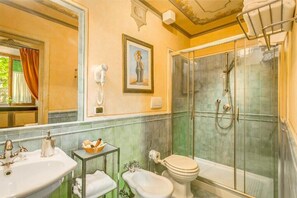 A bathroom with a sink, bidet, toilet, and glass-enclosed shower. - Firenze Suite (Florence)
