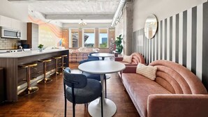Et moderne køkken med en bar, et siddeområde med sofa og stole, samt en stribet væg.