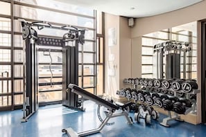 Ein Fitnessraum mit Gewichtstrainingsgeräten, einer Hantelbank und einem Dumbbell-Ständer.