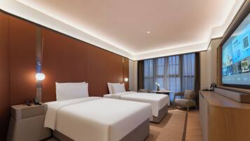 A hotel room with two beds, a TV, a desk, and a chair.