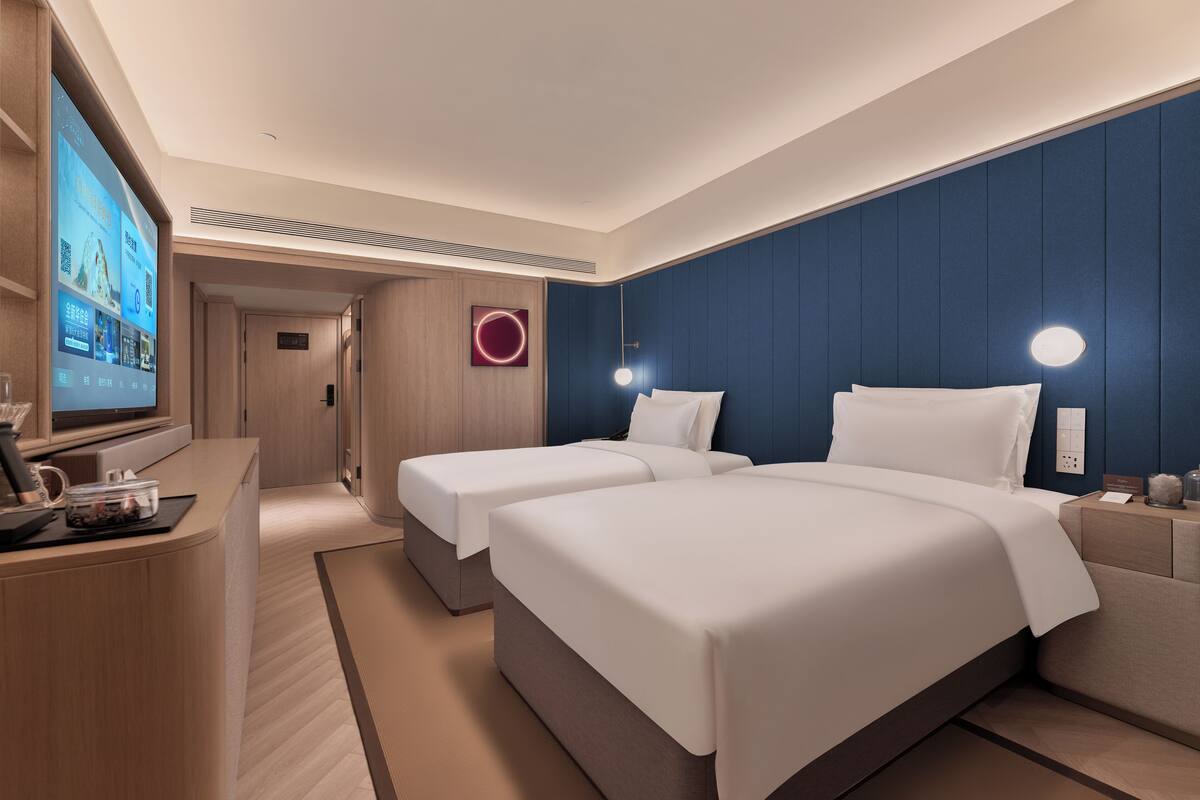 A hotel room with two beds, a TV, and a desk with a coffee maker.