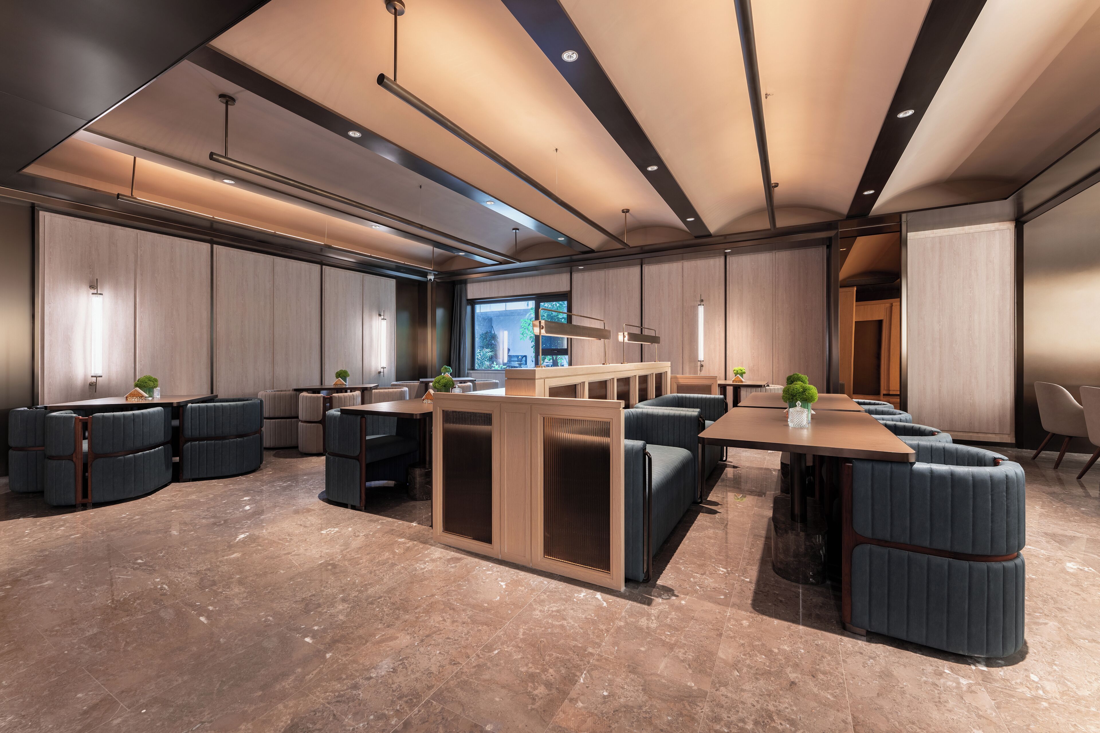 A modern hotel lobby with a central seating area, large windows, and a high ceiling with recessed lighting.