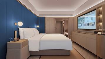 Una habitación de hotel moderna con una cama grande, un televisor montado en la pared y un armario de madera.