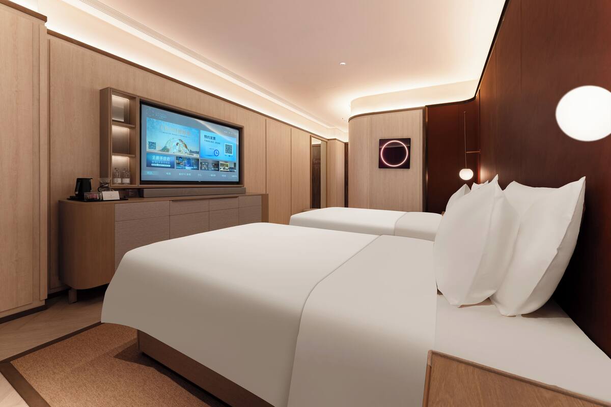 A modern hotel room with a large bed, a flat-screen TV, and a wooden headboard.