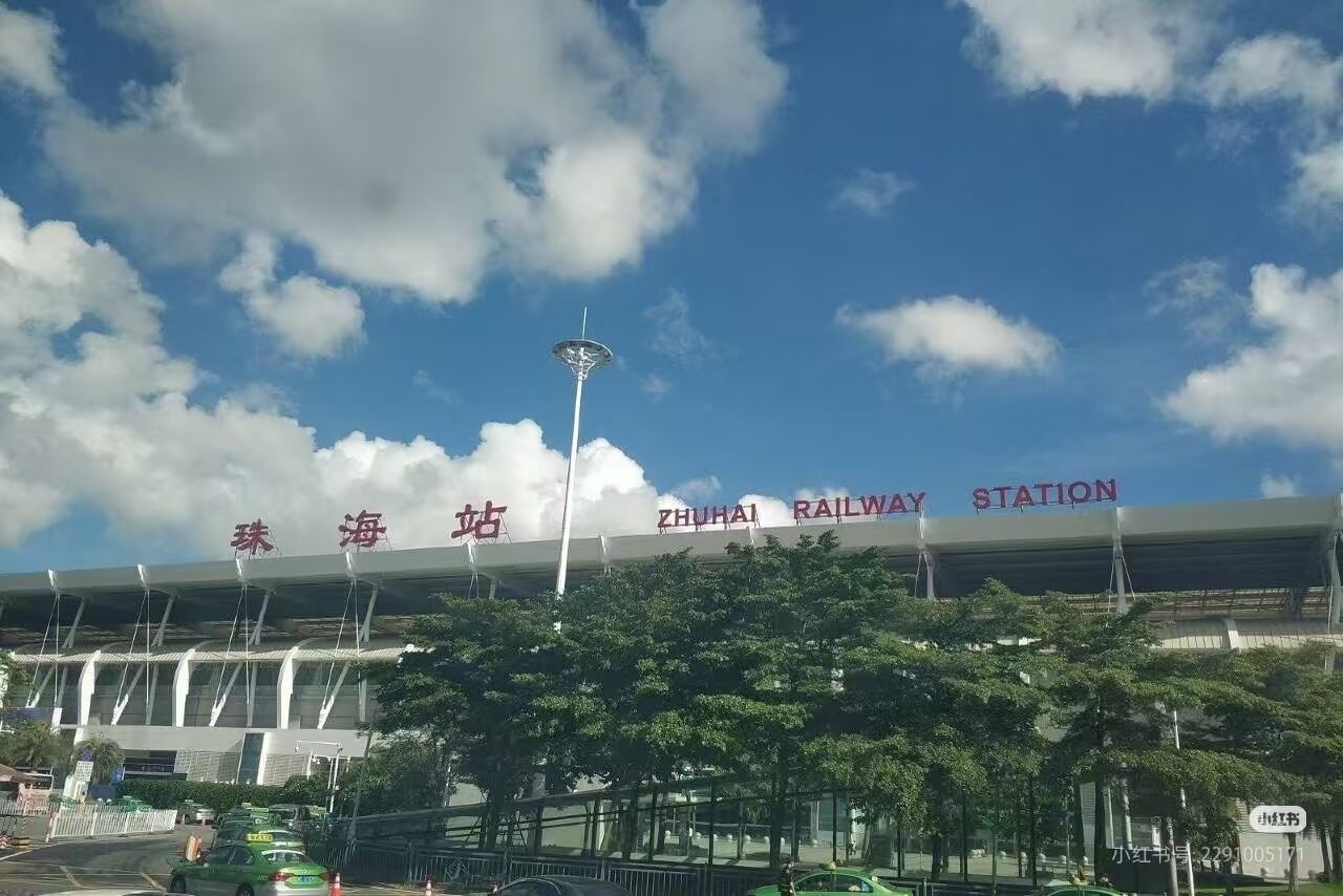 Ein Bahnhof mit modernem Design, ein auffälliges Schild in einer Fremdsprache und ein klarer Himmel mit Wolken.