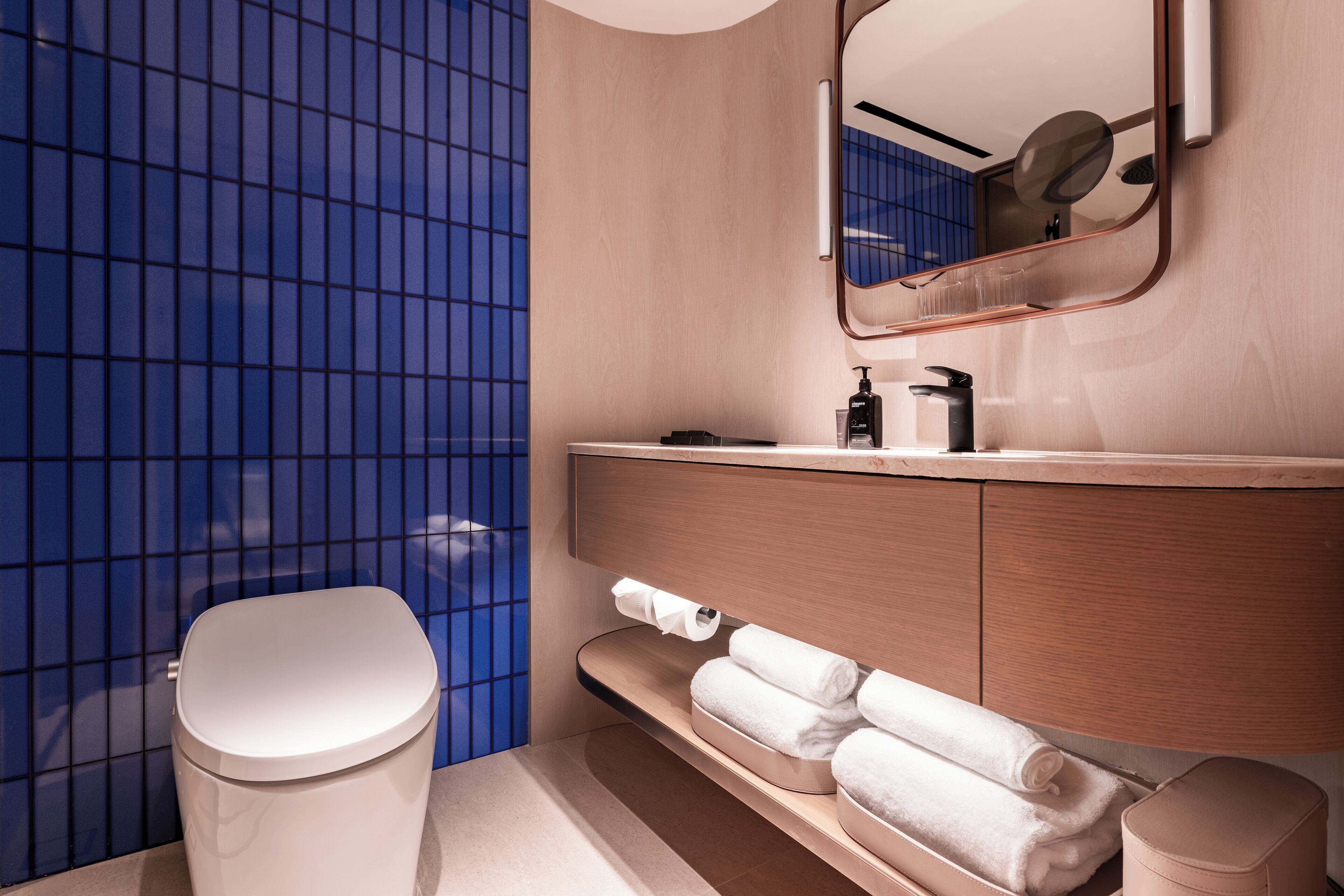 Une salle de bain moderne équipée de toilettes, d’un lavabo avec miroir et d’un porte-serviettes.
