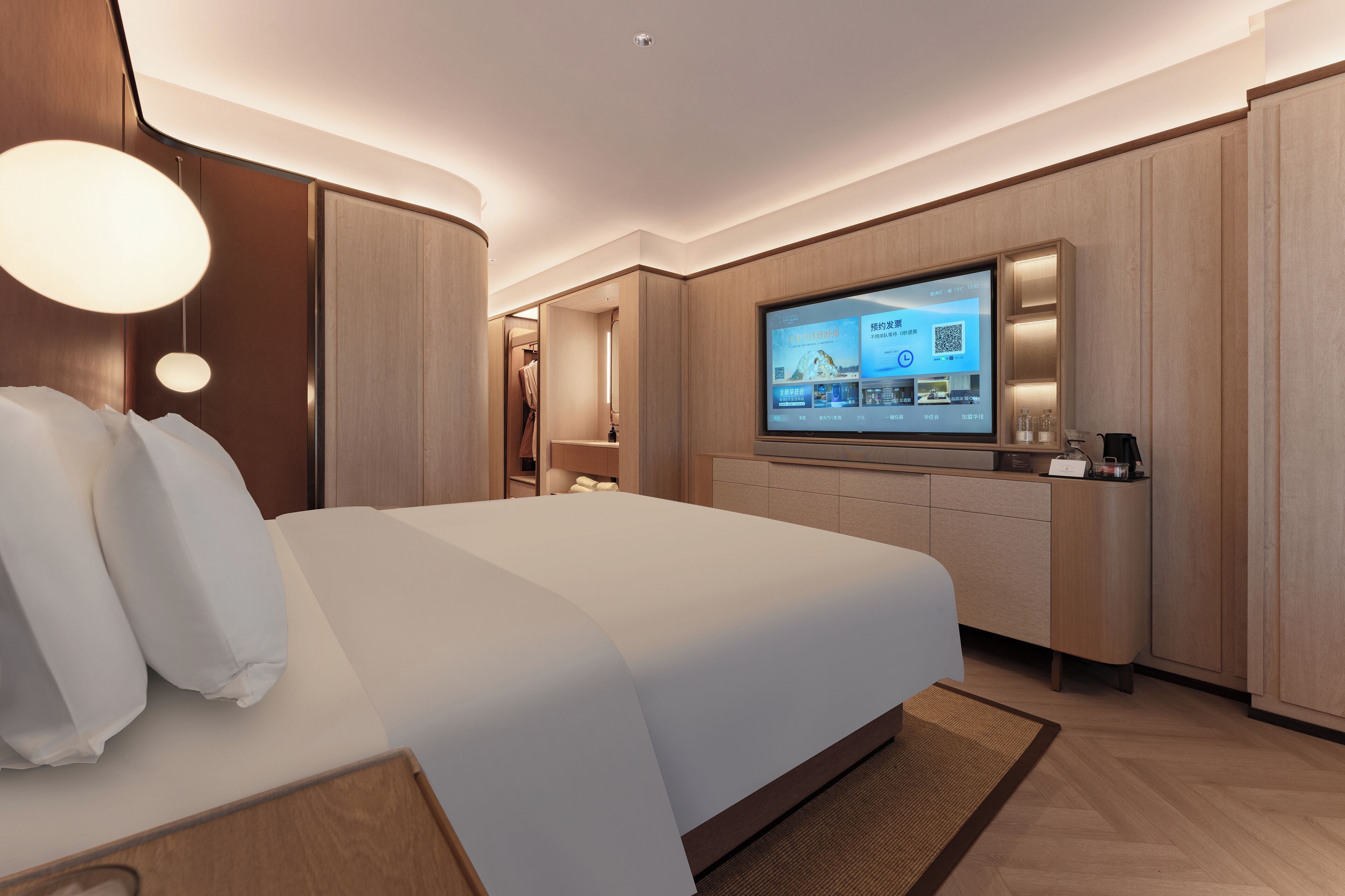 A modern hotel room with a large bed, a flat-screen TV, wooden paneling, and a built-in desk area.