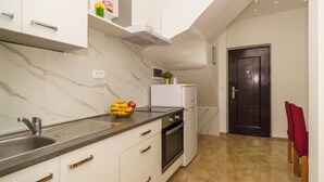 A modern kitchen with a marble backsplash, stainless steel appliances, and a black door. - Vacation apartment with fantastic sea views in Dramalj (Dramalj)