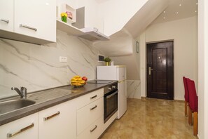 A modern kitchen with a marble backsplash, stainless steel appliances, and a black door. - Vacation apartment with fantastic sea views in Dramalj (Dramalj)