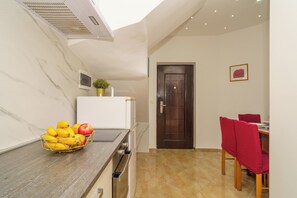 A kitchen with a marble countertop, a fruit bowl, a refrigerator, and a dining area with red chairs. - Vacation apartment with fantastic sea views in Dramalj (Dramalj)