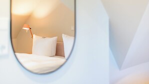 A circular window view of a bed with white bedding and a single bedside lamp. - Friesenhaus Käpt'n Hahn, house part 04 (Westerland)
