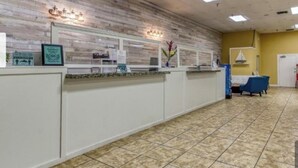 A reception area with a counter, a blue chair, and a tiled floor. - Spacious 2BR Condo at Harbourside Resort, Walk to Beach (Indian Rocks Beach)