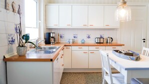 A kitchen with white cabinets, a wooden countertop, a sink, a coffee maker, and a hanging light fixture. - Vacation Rental "LOTTTALEBEN 1" for up to 4 people (non-smoking) (Timmendorfer Strand)