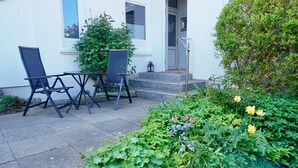 A patio with outdoor seating, a stone pathway, and a garden with various plants and flowers. - Vacation Rental "LOTTALEBEN 2" for up to 2 people (non-smoking) (Timmendorfer Strand)