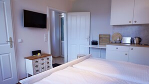 A bedroom with a bed, a TV, a desk with a computer, and a kitchenette. - Vacation Rental "LOTTALEBEN 2" for up to 2 people (non-smoking) (Timmendorfer Strand)