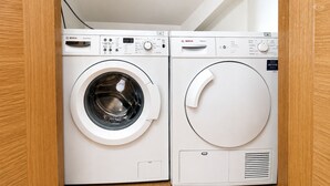 Eine Waschmaschine von Bosch mit Bedienfeld, ein Trockner und ein Abluftschlauch.
