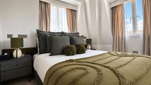 Ein Hotelzimmer mit einem Bett, zwei Nachttischen, einer Lampe und Blick auf den Himmel.