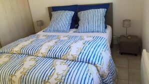 A bed with striped bedding, two bedside tables, and a lamp. - Unique Villa Claire de Lune - Jacuzzi - Swimming pool (Sainte-Maxime)