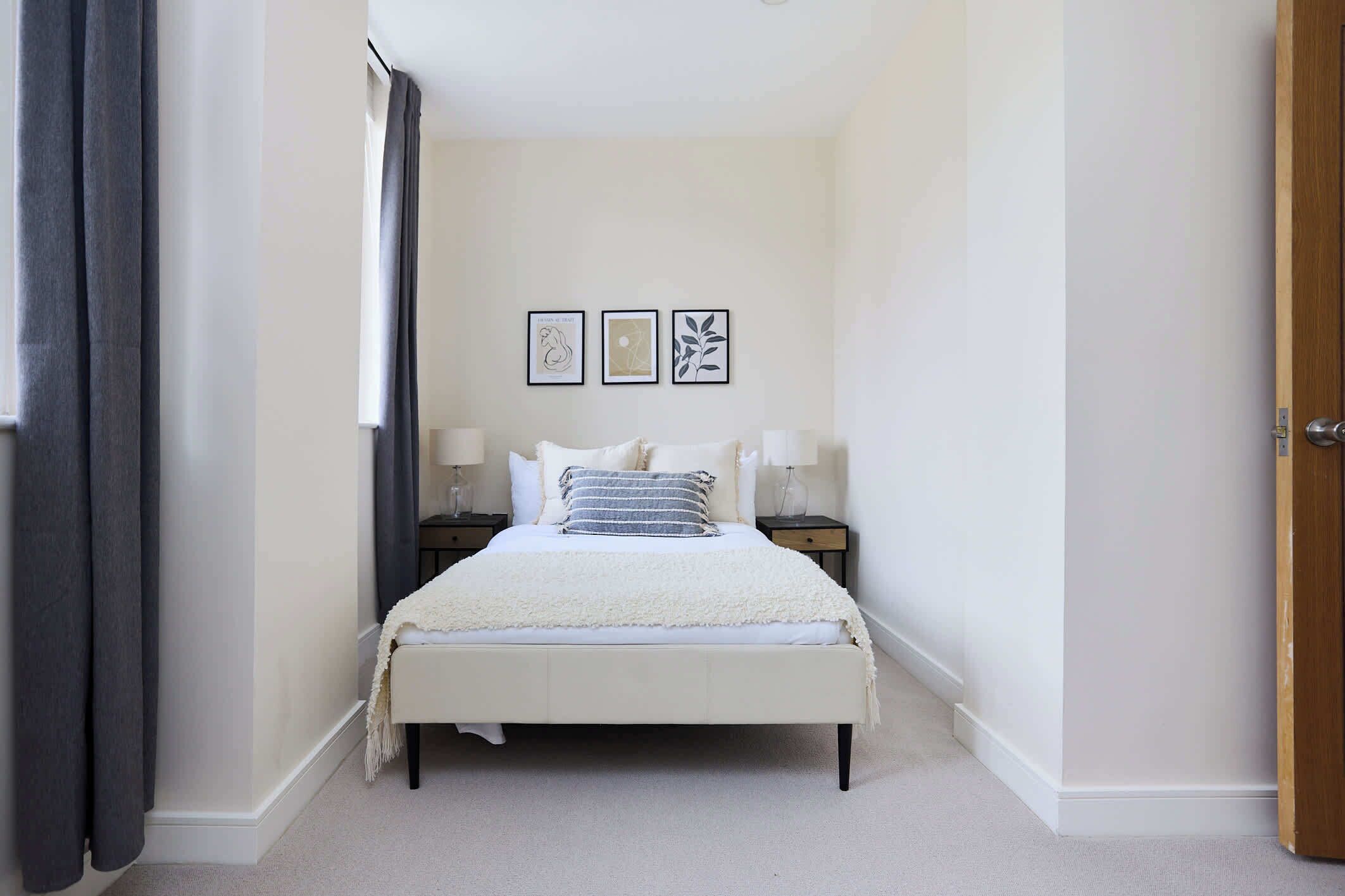 A bedroom with a bed, bedside tables, and wall art.