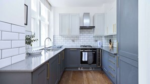 Une cuisine moderne avec des meubles gris, un pare-feu blanc et un plancher en bois.