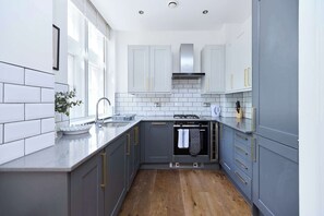 Eine moderne Küche mit grauen Schränken, einer weißen Spritzschutzwand und einem Holzboden.