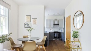 Une cuisine moderne avec des meubles gris, une cuisinière noire et une porte en bois.
