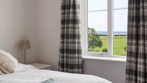 A bedroom with a bed, a nightstand, a lamp, and a window with curtains. - Spacious Home, Private Parking & Garden, Tintagel (Tintagel)