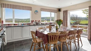 A kitchen with a dining area, large windows, and a view of the countryside. - Spacious Home, Private Parking & Garden, Tintagel (Tintagel)