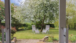A garden with two lawn chairs, a stone wall, and a grassy lawn. - Harbins Farm (Sherborne)