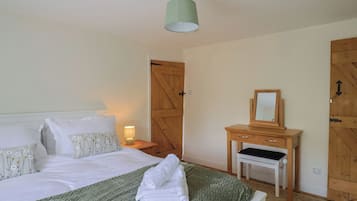 A bedroom with a bed, a bedside table with a lamp, a wooden dresser, and a door.