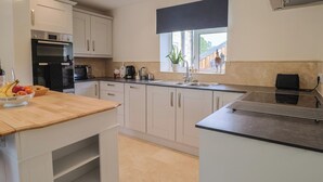 A modern kitchen with white cabinets, a wooden countertop, a built-in oven, and a window with a view. - Harbins Farm (Sherborne)