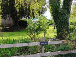 A wooden fence with a sign reading 'Harbins Farm' in a lush garden setting. - Harbins Farm (Sherborne)
