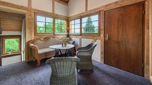 A room with wooden beams, large windows, wicker furniture, and a door.