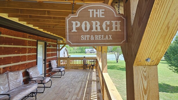 A wooden porch with a sign that reads 'The Porch Sit & Relax.'
