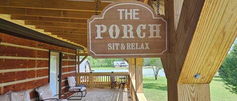 A wooden porch with a sign that reads 'The Porch Sit & Relax.'