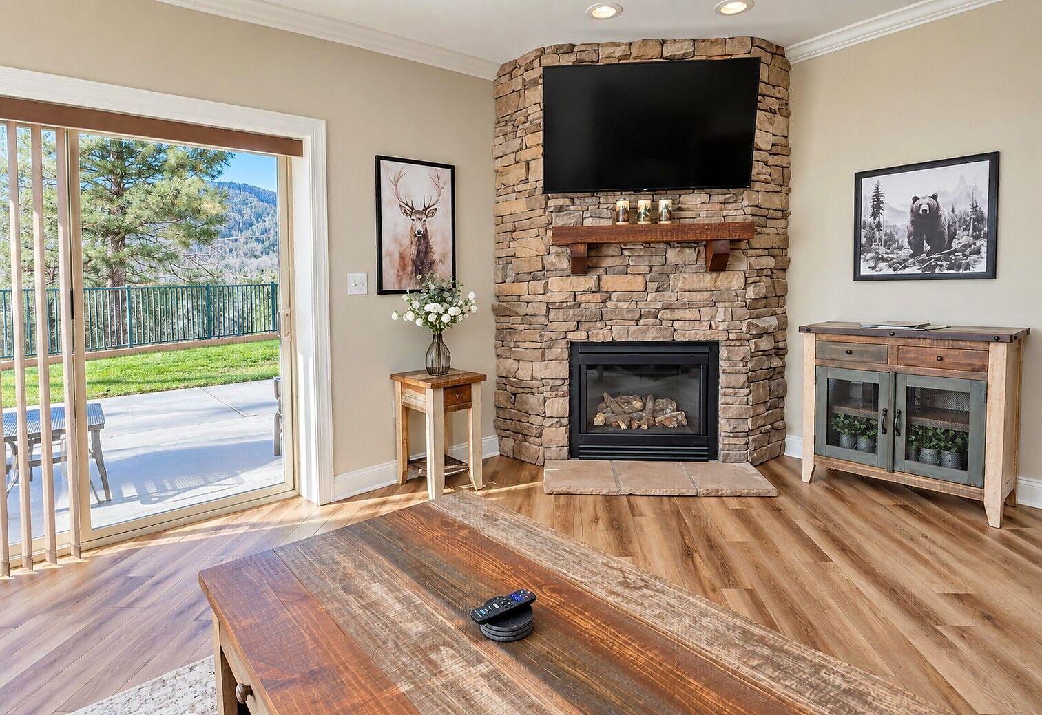 A living room with a stone fireplace, a flat-screen TV, and a wooden coffee table.