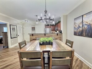 A dining area with a wooden table, chairs, a chandelier, and a kitchen in the background. - UPDATED Downtown Gatlinburg on the strip, Heated Pool, Hot tub (Gatlinburg)