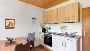 A compact kitchen with wooden cabinets, a built-in oven, and a sink. - Apartment 'In The House Juist' with Private Terrace and Wi-Fi (Dornum)