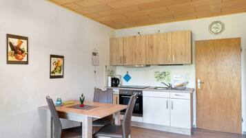 A compact kitchen with wooden cabinets, a built-in oven, and a dining area with a table and chairs.