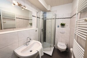 A modern bathroom with a glass-enclosed shower, a sink, and a toilet. - Seahorse: Quiet vacation apartment with balcony near the beach in Büsum (Büsum)