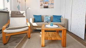 Ein Wohnzimmer mit einer Couch, einem Sessel, einem Couchtisch und einem Bild an der Wand.