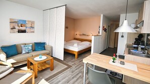 Ein kompakter Wohnbereich mit Sofa, Bett, Essbereich und einer Küchenzeile.