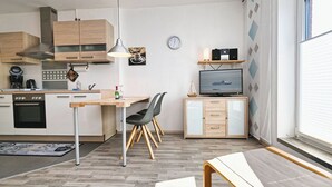 Eine moderne Küche mit Holzschränken, einem eingebauten Backofen und einem Essbereich mit Tisch und Stühlen.