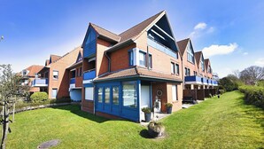 Ein Mehrfamilienhaus mit mehreren Stockwerken, großen Fenstern und einem geneigten Dach.