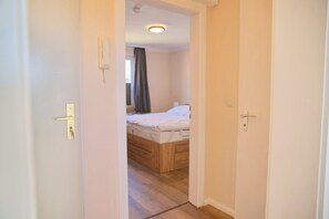 Ein Schlafzimmer mit einem hölzernen Bett, einem weißen Nachttisch und einer Tür mit Schlüsselloch.