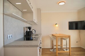 Eine moderne Küche mit Einbauherd, einer Kaffeemaschine und einem Barhocker.