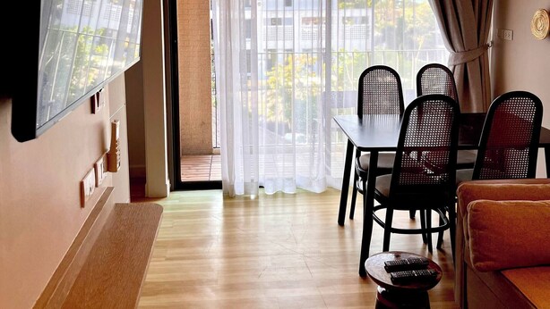 A modern living room with a flat-screen TV mounted on the wall, a dining area with a table and chairs, and a sofa. - Coconut Suite Aonang (Krabi)