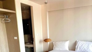 A bedroom with a bed, white linens, a hanging lamp, and a wooden floor. - Coconut Suite Aonang (Krabi)