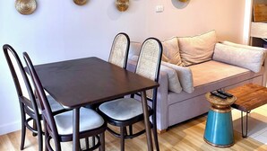 A modern dining area with a dark wooden table and chairs, a light-colored sofa, and decorative wall art. - Coconut Suite Aonang (Krabi)