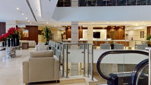 Un vestíbulo moderno de hotel con una zona de estar, un mostrador de recepción y una escalera.